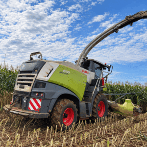 Colhedora de forragem CLAAS Jaguar 860 vista pela lateral e traseira em lavoura de milho.